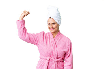 Middle age caucasian woman in a bathrobe over isolated background doing strong gesture
