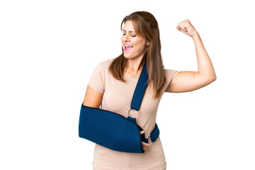 Middle age with broken arm and wearing a sling over isolated background celebrating a victory