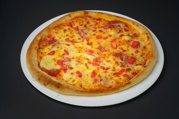 Closeup shot of a pizza Margherita on a white plate placed on a black table