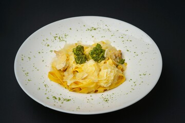 Closeup shot of Broccoli pasta decorated in a white plate on a black background