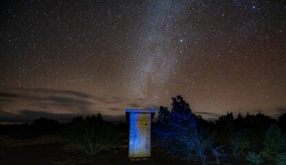 Naklejka na ściany i meble Wooden outdoor toilet in nature under a beautiful dark starry night sky