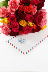 A letter in an envelope and a bouquet of roses on a white background. Congratulations on the holiday. Vertical photo. Copy space.