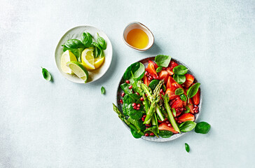 Spring salad with strawberries, pomegranate, asparagus, spinach, basil leaves and citrus-honey dressing. Top view - 590468456