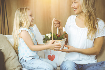 Happy mother day. Child daughter congratulates mom and gives her basket of spring flowers. Family concept