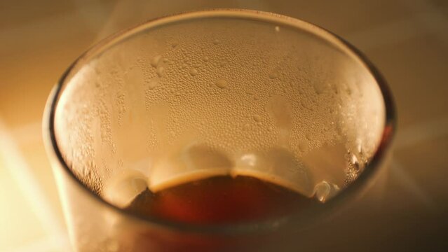 Hot steam comes from freshly brewed black coffee in a glass, alternative beverage making process 4K macro slow motion footage.