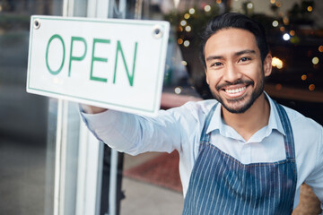 Happy Asian man, small business and smile with open sign on window for service in coffee shop or restaurant. Portrait of male entrepreneur holding billboard or poster for opening retail store or cafe