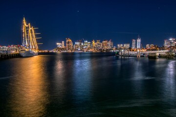 Fototapeta na wymiar Beautiful view of a sailboat near the cityscape at night