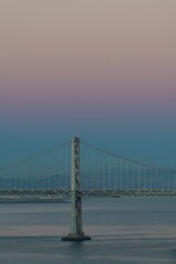 The Oakland Bay Bridge on the water under a pink and blue sky in San Francisco, California