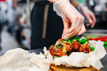 woman chef cooking chicken wings in a sauce in the kitchen