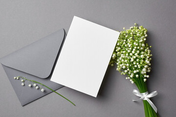 Paper invitation or greeting card mockup with envelope and lily of the valley flowers