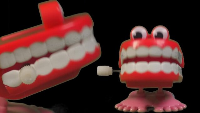 Two fun toy chattering teeth sharing a chatty joke. Jokes and toys two clockwork chattering teeth chatting together in slow motion.
