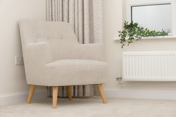 Neutral colour home interior showing beige chair, carpet and curtains