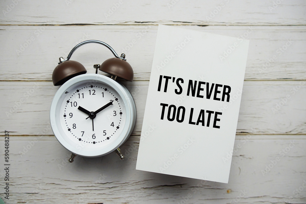 Poster it's never too late text message with alarm clock top view on wooden background