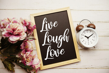 Live Lough Love text message with alarm clcok and flower decoration on wooden background