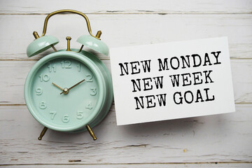 New Monday New Week New Goal text message with alarm clock top view on wooden background