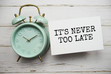 It's never too late text message with alarm clock top view on wooden background