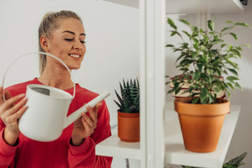 A smiling woman enjoys taking care of her houseplants