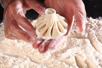 Preparation of khinkali. Khinkali is formed manually before cooking.Before cooking, roll Georgian khinkali in flour. Selective focus.