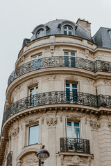 Exterior of aged residential building of beige color with glass windows and beautiful cast iron balconies located in the center of Paris, France