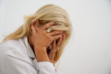 portrait of sad senior female doctor and depression covering her face with her hands. Psychological problems and mental health