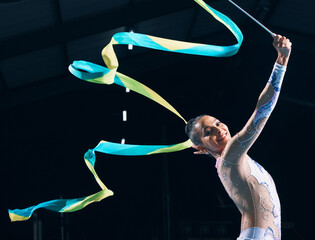 Ribbon gymnastics, happy woman and portrait of dancer in performance, training show and competition in dark arena. Female, rhythmic movement and smile for action, creative talent and sports concert