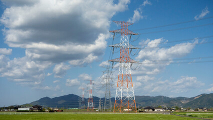 青空と雲、後ろに帆柱山、筑豊平野の高圧送電線鉄塔。Blue sky and clouds, Mt. Hobashira in the background, and high-voltage power transmission towers in the Chikuho plains.