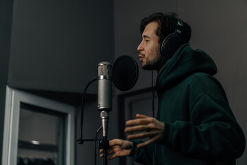 singer with headphones and microphone emotionally recording a new song in a professional recording...
