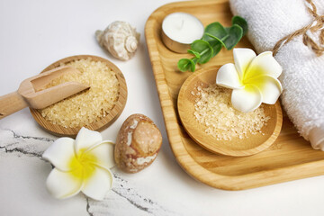 Obraz na płótnie Canvas Spa and bathroom accessories on wooden tray, bath sea salt on wooden spoon, towel, sea stone, white orchids. Spa and massage products set conception. Top veiw