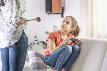Mother-daughter disagreement with strict mother telling girl off for being online all the time