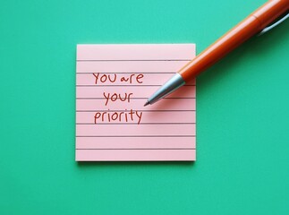 Note pad on green background with handwritten text YOU ARE YOUR PRIORITY, concept of shift  people...