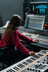 beautiful young sound engineer in bright clothes used digital audio mixer presses keys control panel