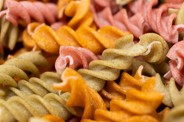 Rice vegetable pasta in the form of spirals, top view. Healthy rice pasta with tomatoes, celery, carrots and beets