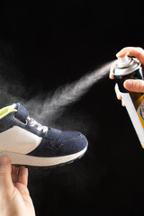 A woman applies a spray from a cylinder with a water-repellent liquid to children's shoe. Care for...
