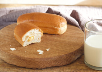 French brioche buns with cream lie on a wooden board. Nearby is a glass of milk