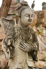 Fototapeta na wymiar Ancient sandstone sculptures dressed like Chinese people in various poses at Wat Pho, Bangkok, Thailand.