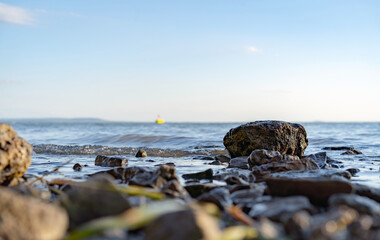 Lake shore stones at sunset. Horizont view in the background. Yellow buoy.