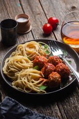 Pasta with meatballs and sauce in a plate on a wooden table