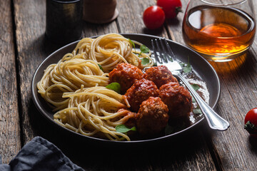 Pasta with meatballs and sauce in a plate on a wooden table