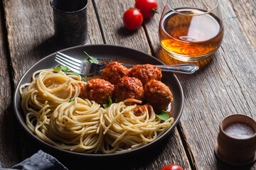 Pasta with meatballs and sauce in a plate on a wooden table