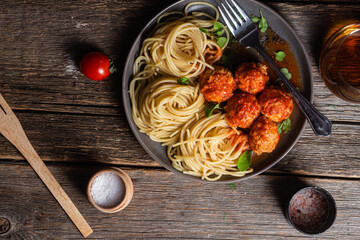 Pasta with meatballs and sauce in a plate on a wooden table