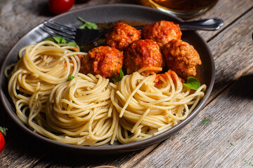 Pasta with meatballs and sauce in a plate on a wooden table