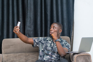 African businessman seated chatting with his client via a conference video call with his mobile phone
