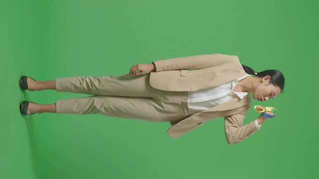 Full Body Of Asian Business Woman In A Suit Kissing A Gold Medal In Her Hand Being Proud Winning As The First Winner On Green Screen Background In The Studio
