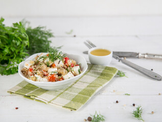 Fresh salad with quinoa, feta cheese and fresh tomatoes. Lean vegetarian. White wooden background.