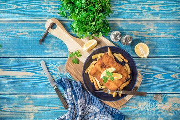 A piece of fried cod with fries on a plate.