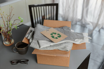 Box with used wardrobe for reuse and card with circular economy logo. Reusing, recycling materials...
