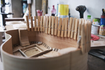 close-up of the body of a guitar under construction with clamps that improve the adhesion of the glue.