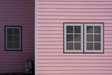 Fototapeta premium Sunlight on surface of Glass and Wooden Windows on artificial wood Wall of Pastel pink House in Vintage style , front view with copy space
