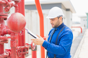 The engineer is inspecting the safety equipment on the fire extinguishing system.The system engineer is checking the pressure and recording it with Clipboard or checking .
