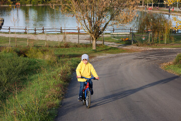 Kid boy of 6 years with bicycle on park road. Healthy lifestyle, environmentally transport concept.